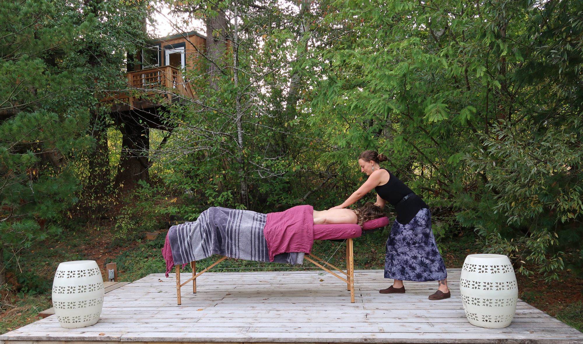 A massage table set up on a cedar deck surrounded by trees