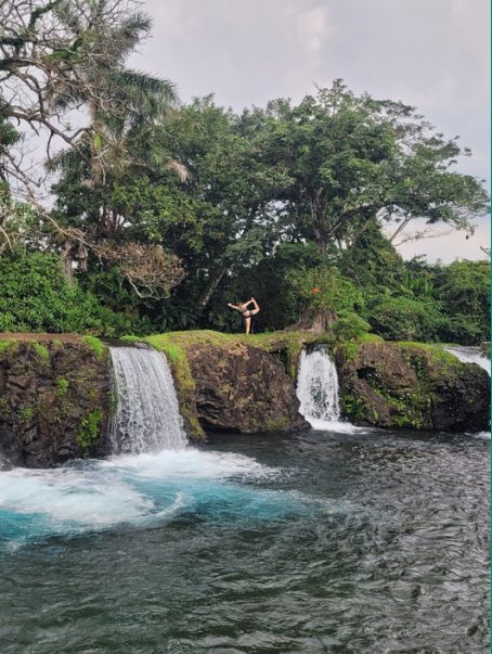 A yoga pose held on a mossy ledge above falling water